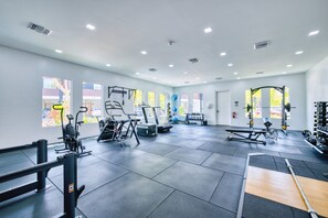 A gym with various exercise equipment, large windows, and a clean, modern design. - Lush Oasis in the heart of 7mile Beach Area (George Town)