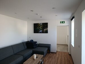 A modern waiting area with a grey sectional sofa, a wooden coffee table, and a framed nature photograph on the wall.