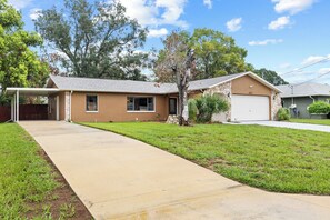 A single-story house with a covered patio, a front yard, and a garage. - Pet-Friendly  Weeki Wachee Springs  Pine Island (Spring Hill)