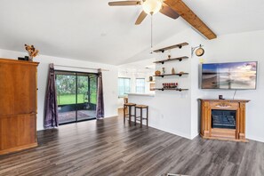 A spacious living room with a large wooden cabinet, a fireplace, and a ceiling fan. - Pet-Friendly  Weeki Wachee Springs  Pine Island (Spring Hill)