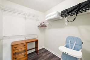 A room with a wooden dresser, a baby changing station, and a wall-mounted shelf with clothes. - Pet-Friendly  Weeki Wachee Springs  Pine Island (Spring Hill)