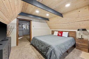 Ein Schlafzimmer mit einem Bett, Nachttischen, einem Kleiderschrank und einer Tür zu einem anderen Raum.