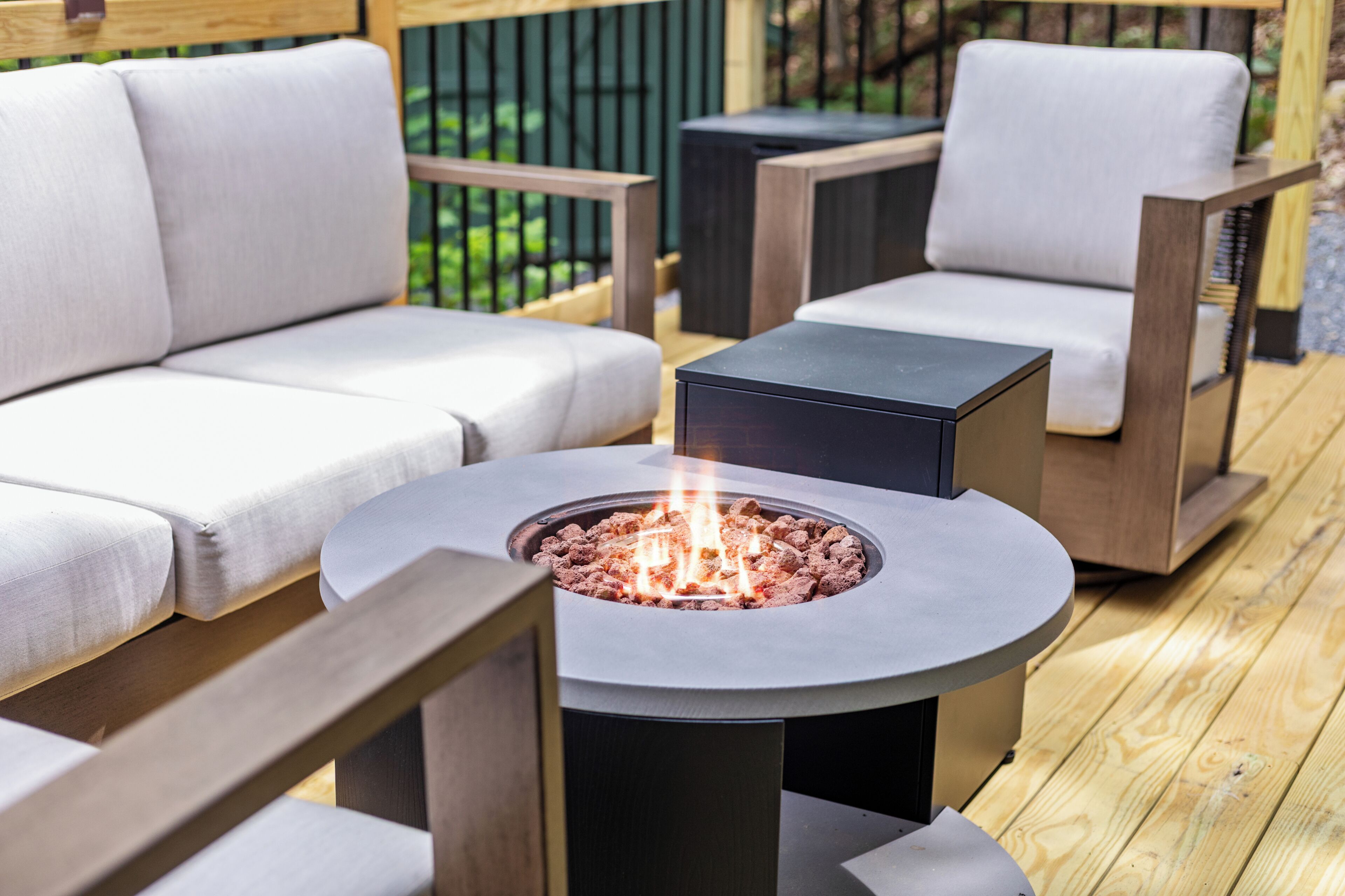 A patio area with a round table, two chairs, and a built-in fire pit.