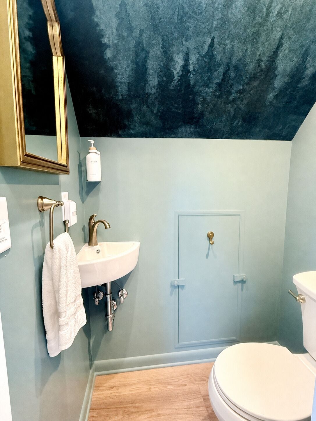 Un baño con un lavamanos blanco, una toalla colgada en la pared, una puerta y un inodoro.