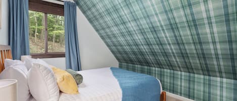 Une chambre à coucher avec un lit, des oreillers, une fenêtre et des rideaux.