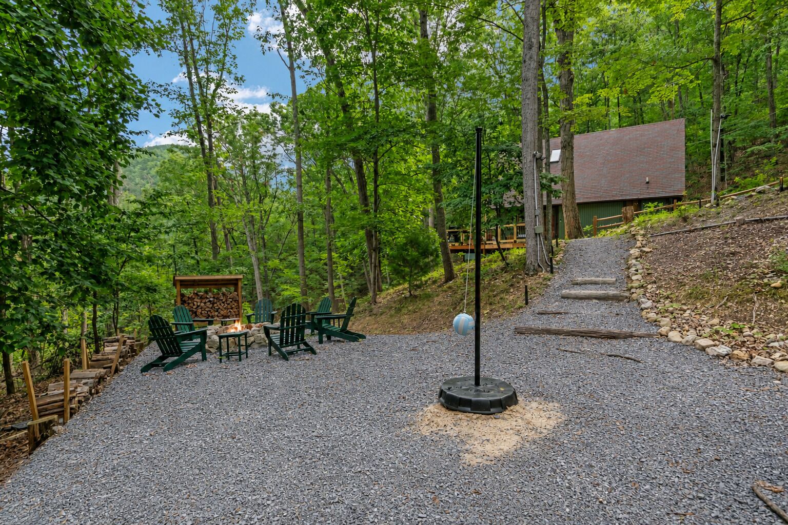 A gravel patio with outdoor seating, a fire pit, and a swing set.