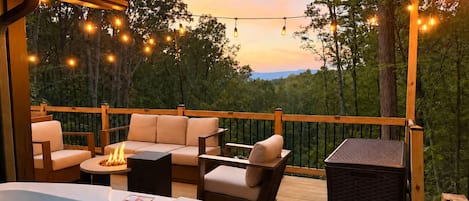 A deck with outdoor seating, a hot tub, and string lights.