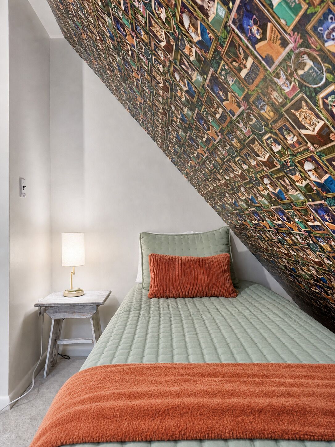 Une chambre à coucher comprenant un lit, une table de chevet, une lampe et un mur orné d’un motif décoratif.