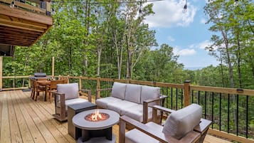 An outdoor deck with a fire pit, seating, and a grill.