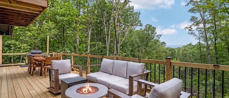 An outdoor deck with a fire pit, seating, and a grill.