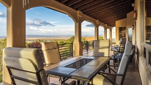Eine Außenpatio mit Tisch und Stühlen, einer Pergola und Blick auf die Landschaft.