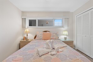A bedroom with a bed, two bedside tables, a window, and a wardrobe. - Sand Caper #702 (Fort Myers Beach)