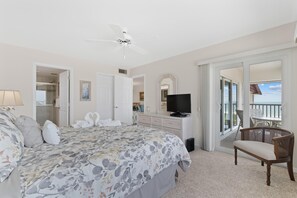Une chambre à coucher avec un lit, une télévision, une chaise et un balcon offrant une vue.