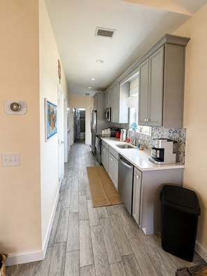 A modern kitchen with grey cabinets, a stainless steel refrigerator, and a coffee maker.