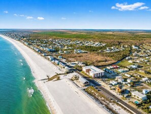 A coastal residential area with houses along the beach, a road, and a river.