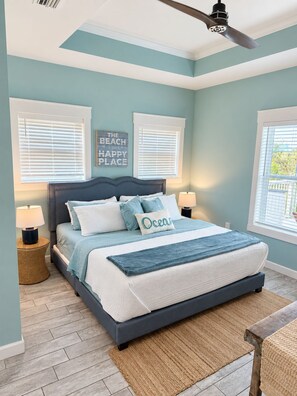A bedroom with a bed, two bedside lamps, a ceiling fan, and a window with blinds.