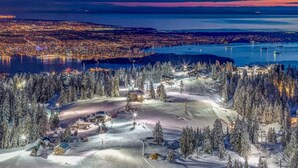 Un centro de esquí cubierto de nieve con una vista panorámica de una ciudad al anochecer.