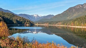 Un lago rodeado de montañas boscosas bajo cielos despejados.