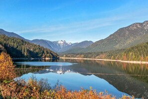 A lake surrounded by forested mountains with clear skies.