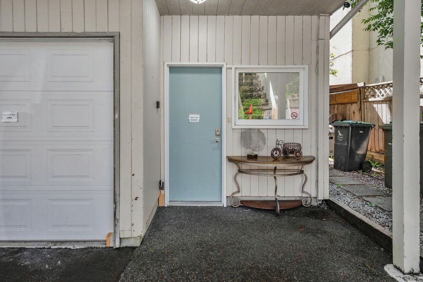 Een garage met een gesloten witte deur, een lichtblauwe deur en een tafeltje met een decoratieve versiering.