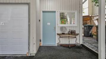 Een garage met een gesloten witte deur, een lichtblauwe deur en een tafeltje met een decoratieve versiering.