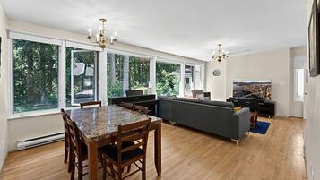 A spacious living room with a dining area, large windows, and a piano.