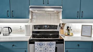 Une cuisine avec des armoires de couleur turquoise, une cuisinière en acier inoxydable et un dosseret carrelé.