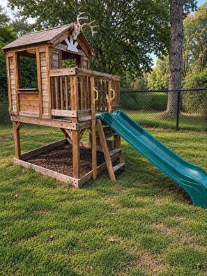 A wooden playhouse with a slide.