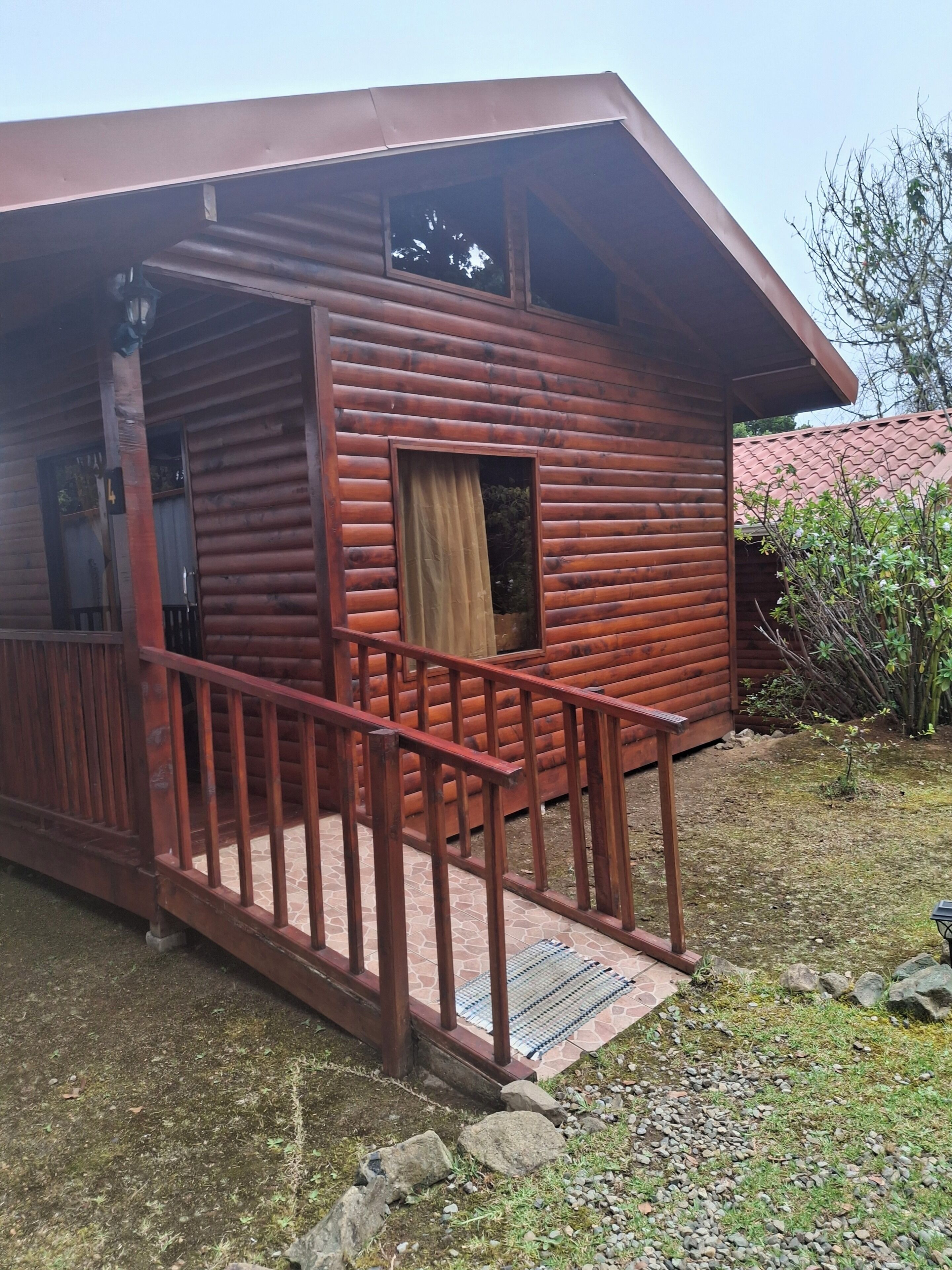 A wooden cabin with a porch and a small window.