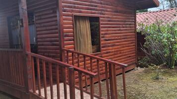 A wooden cabin with a porch and a small window.