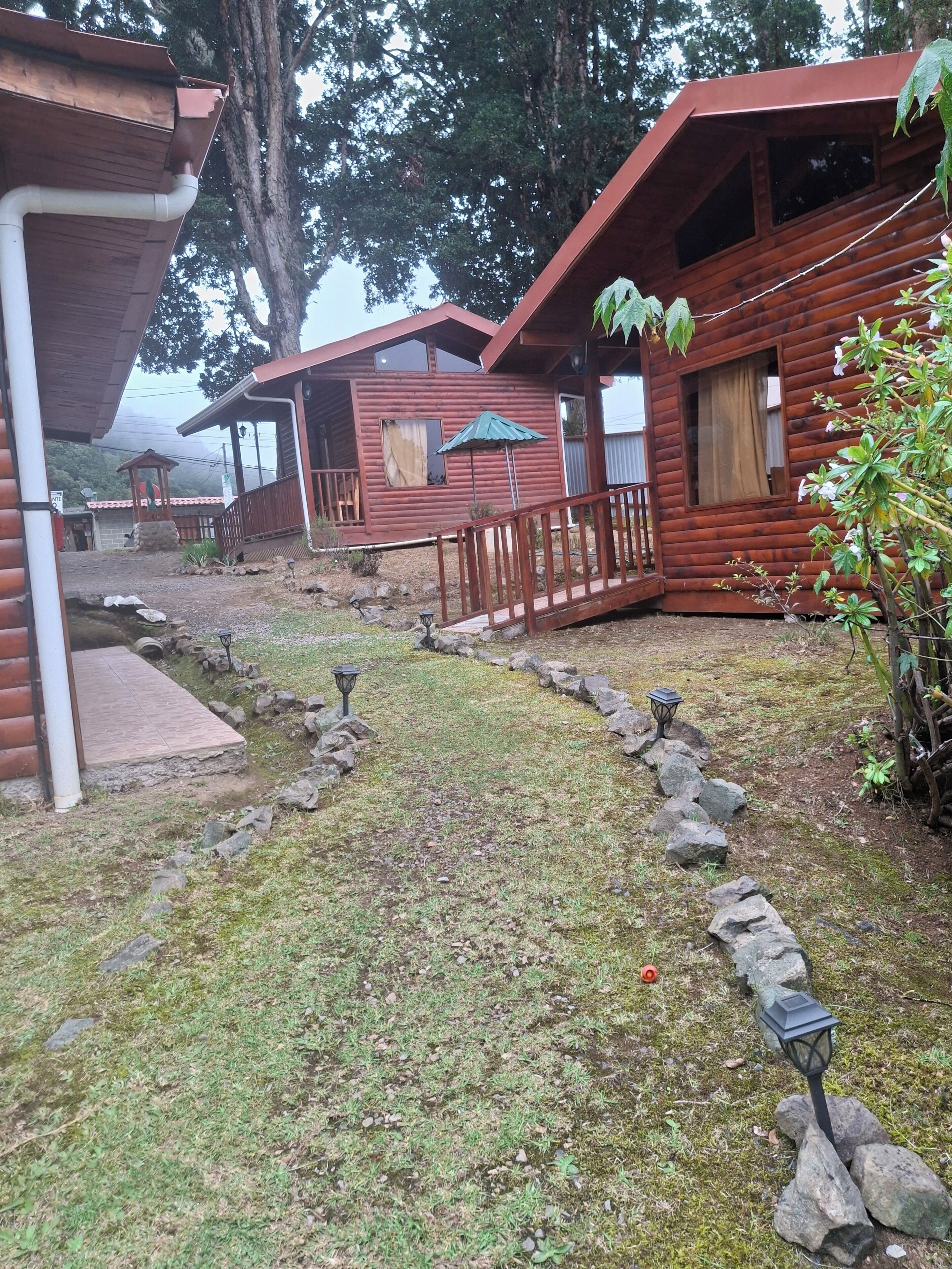 Uma fileira de cabanas de madeira com um caminho de pedra que leva a um gazebo.