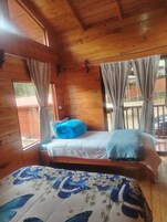 Quarto de cabana de madeira com cama, janela e cortinas.