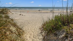 A sandy beach with dunes and sparse vegetation. - Ocean Gate I: Cozy Retreat Near Beach (St. Augustine)