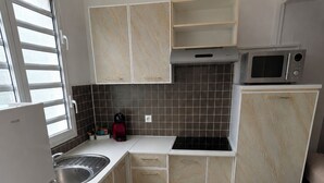 Eine kompakte Küche mit Kühlschrank, Spüle, Mikrowelle und Schränken.
