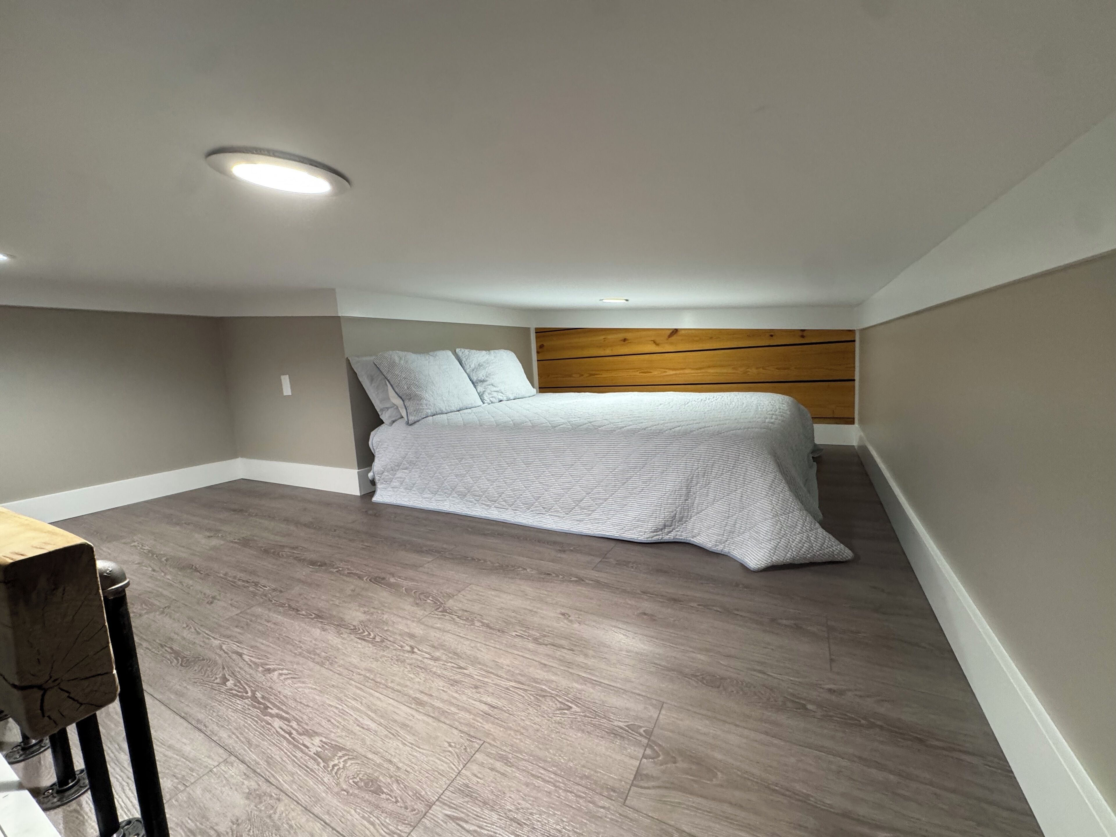 A bedroom with a bed, wooden headboard, and a desk with a chair.