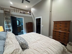 Une chambre avec un lit en mezzanine, une commode en bois et une armoire.
