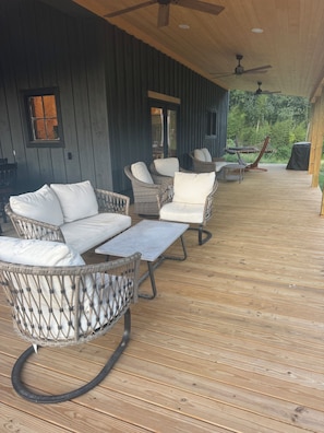 A covered outdoor seating area with wicker furniture and ceiling fans.