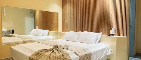 Une chambre d’hôtel moderne avec un grand lit, une table de chevet, un miroir et un mur recouvert de panneaux en bois.