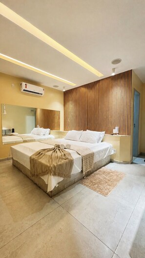 Habitación de hotel moderna con una cama grande, una mesita de noche, un espejo y una pared de paneles de madera.