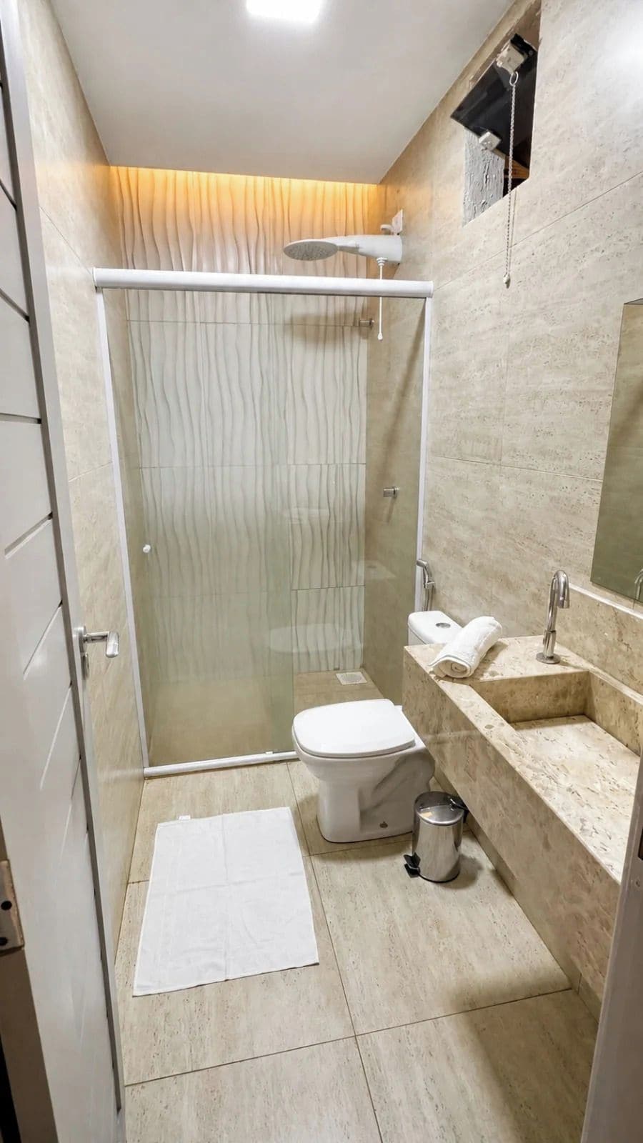 Un baño moderno con cabina de ducha de vidrio, inodoro, lavabo y espejo.