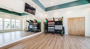 Ein Fitnessstudio mit Holzböden, Trainingsgeräten und großen Fenstern.