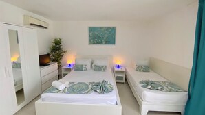 A hotel room with two single beds, a wardrobe, a desk, and a nightstand with lamps. - CARIBBEAN STUDIOS playa LOS CORALES (Punta Cana)
