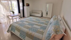 A bedroom with a bed, a sofa, a desk, and a wardrobe. - CARIBBEAN STUDIOS playa LOS CORALES (Punta Cana)