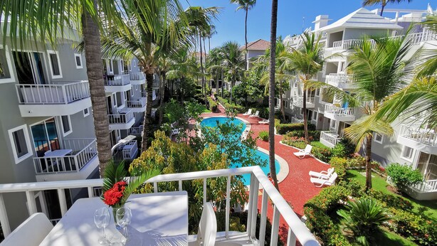 A hotel with multiple balconies, a swimming pool, and lush greenery. - CARIBBEAN STUDIOS playa LOS CORALES (Punta Cana)