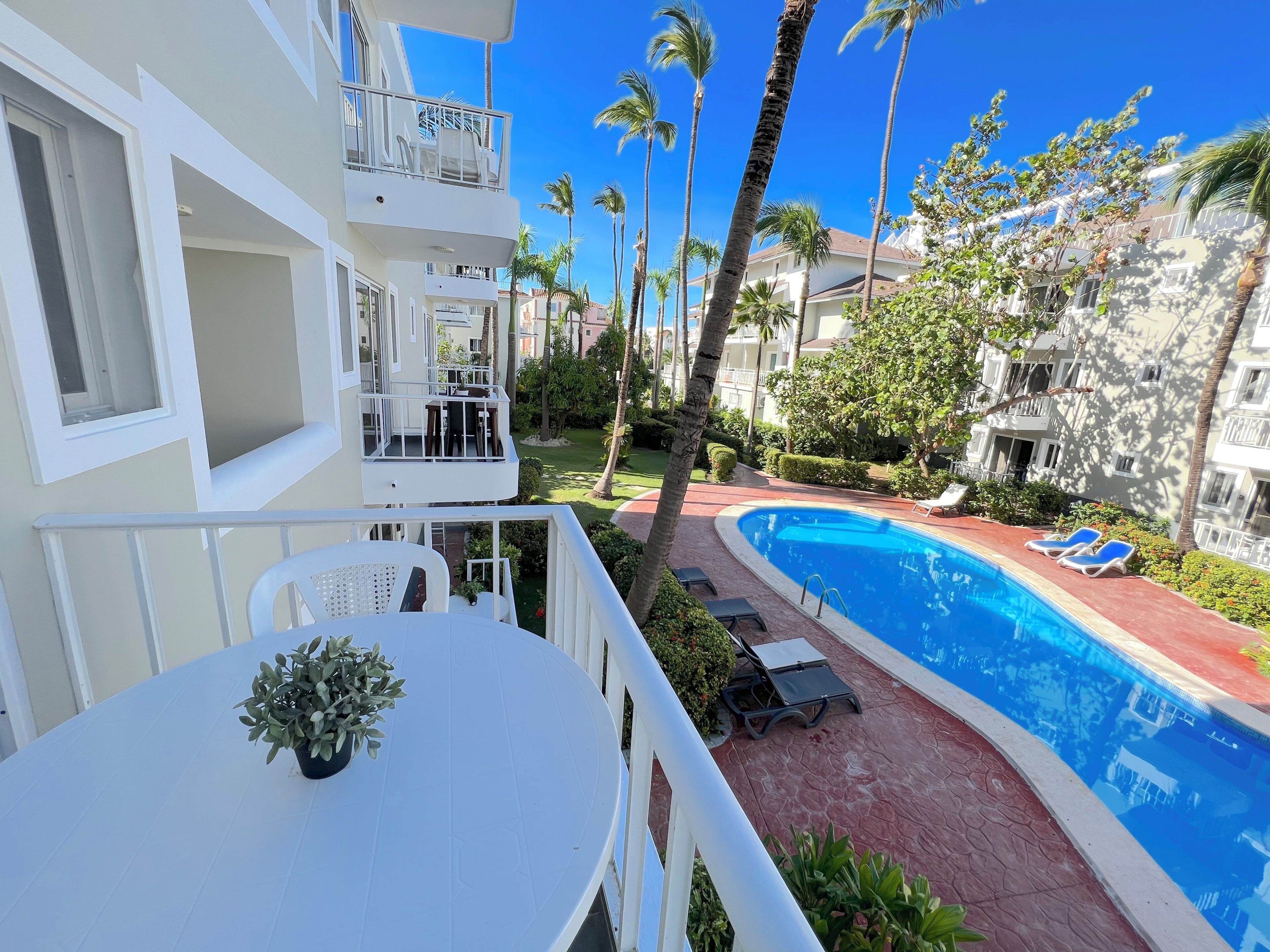 Un hôtel doté d’une piscine, de chaises longues et de palmiers.