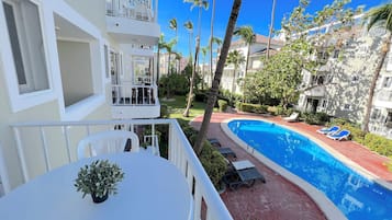 Un hôtel doté d’une piscine, de chaises longues et de palmiers.