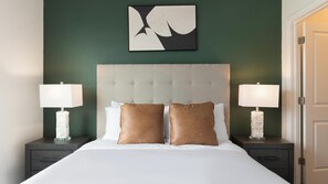 Ein Hotelzimmer mit einem großen Bett, zwei Nachttischen, einem gepolsterten Kopfteil und einem an der Wand befestigten abstrakten Kunstwerk.