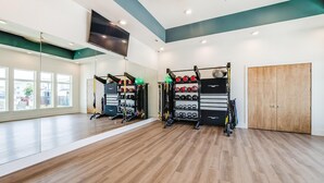 Ein Fitnessstudio mit Holzböden, Trainingsgeräten und großen Fenstern.