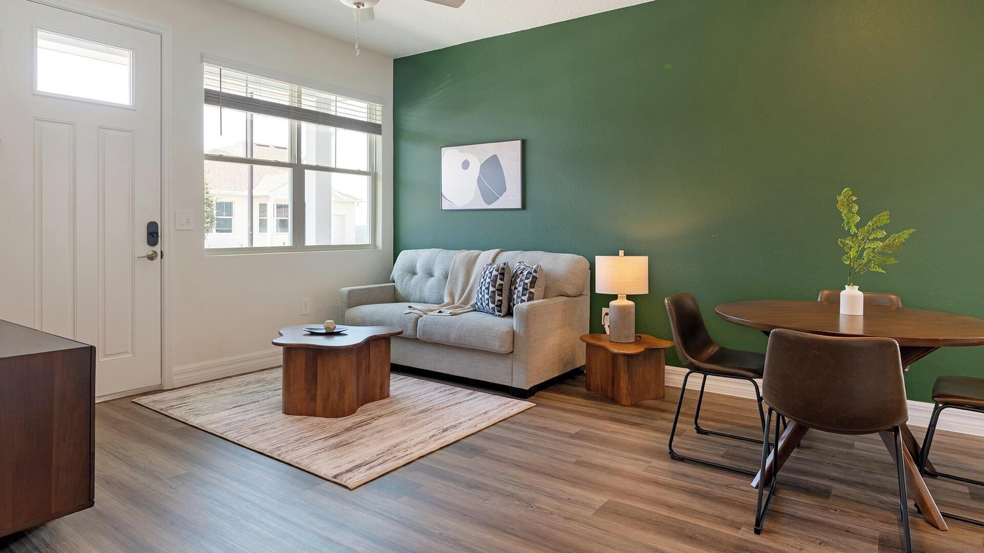 A living room with a sofa, coffee table, and a dining area with chairs and a table.