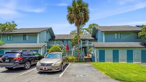 A motel with a parking lot, two cars parked, and a staircase leading to the entrance. - Skiff F7 in Saint Simons Island, GA (Saint Simons Island)